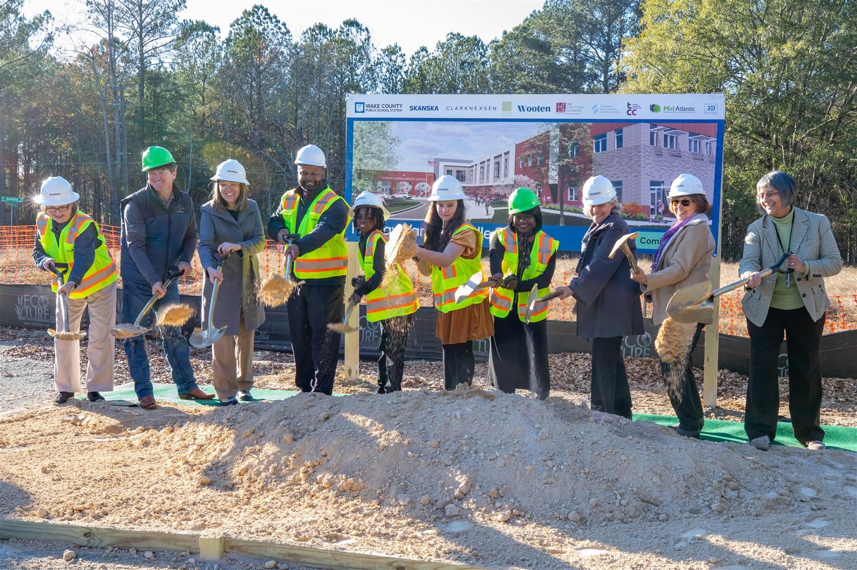The board of education and students scoop dirt for the groundbreaking