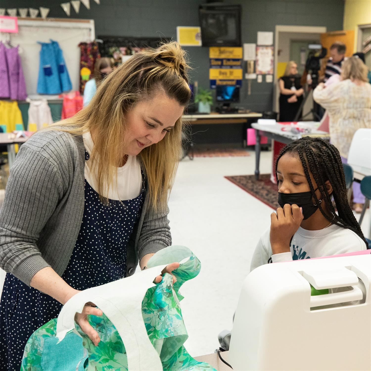  Photo of teacher and student looking at fabric.