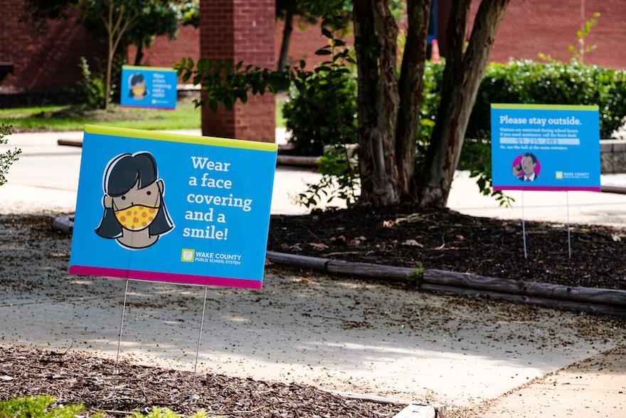 signs reminding about face coverings and social distancing 
