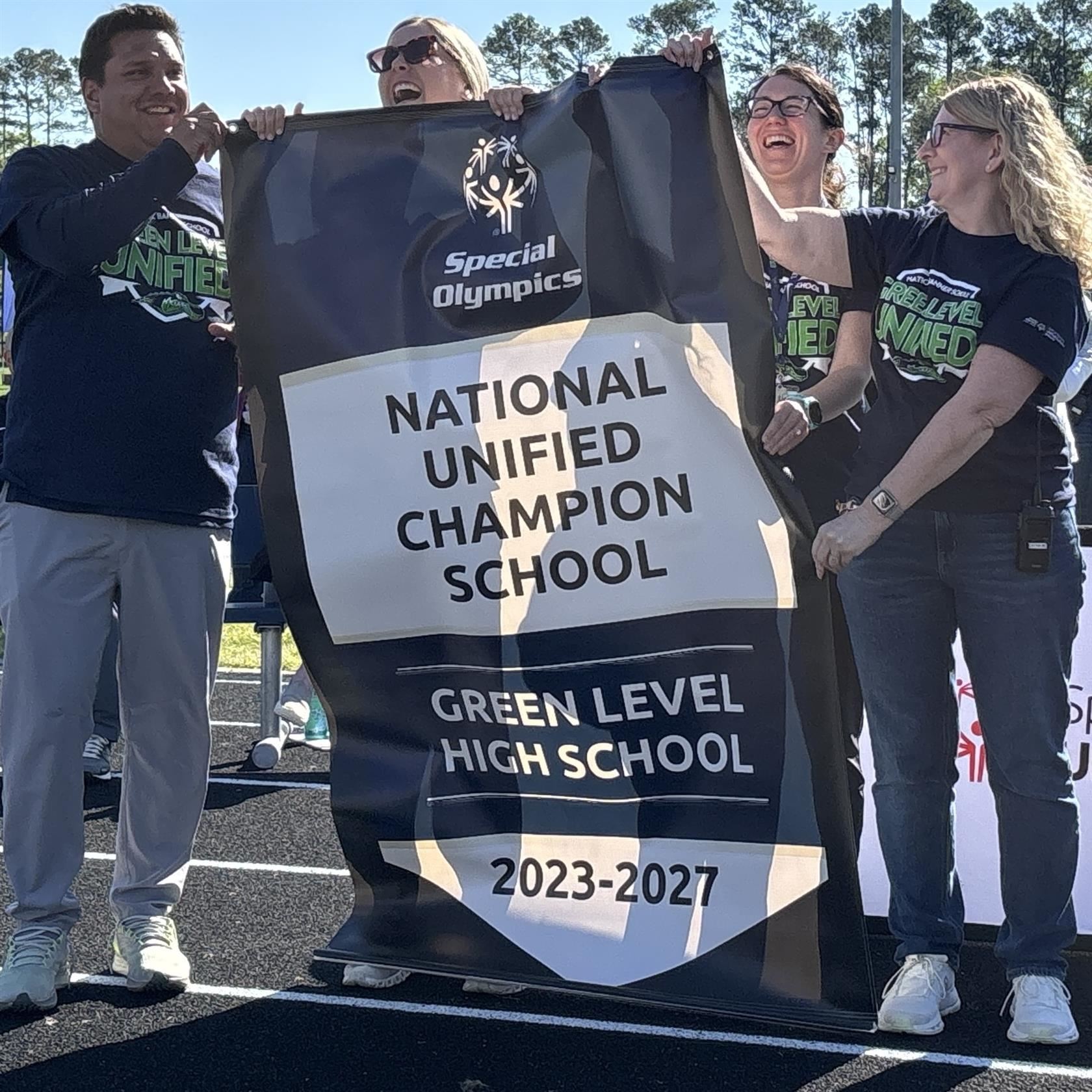  Green Level staff hold Unified Champion banner