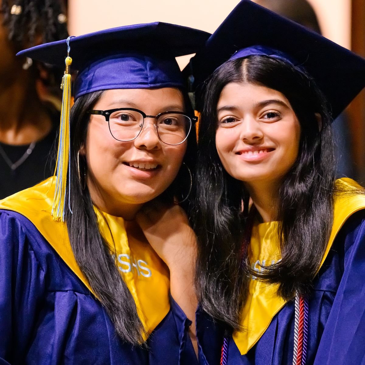 Two graduates smile and pose for a photo 