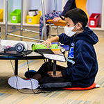  student sitting on the floor looking at a laptop