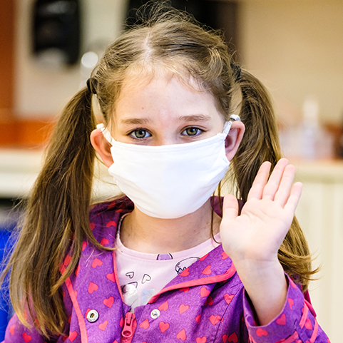  girl wearing a mask and waving