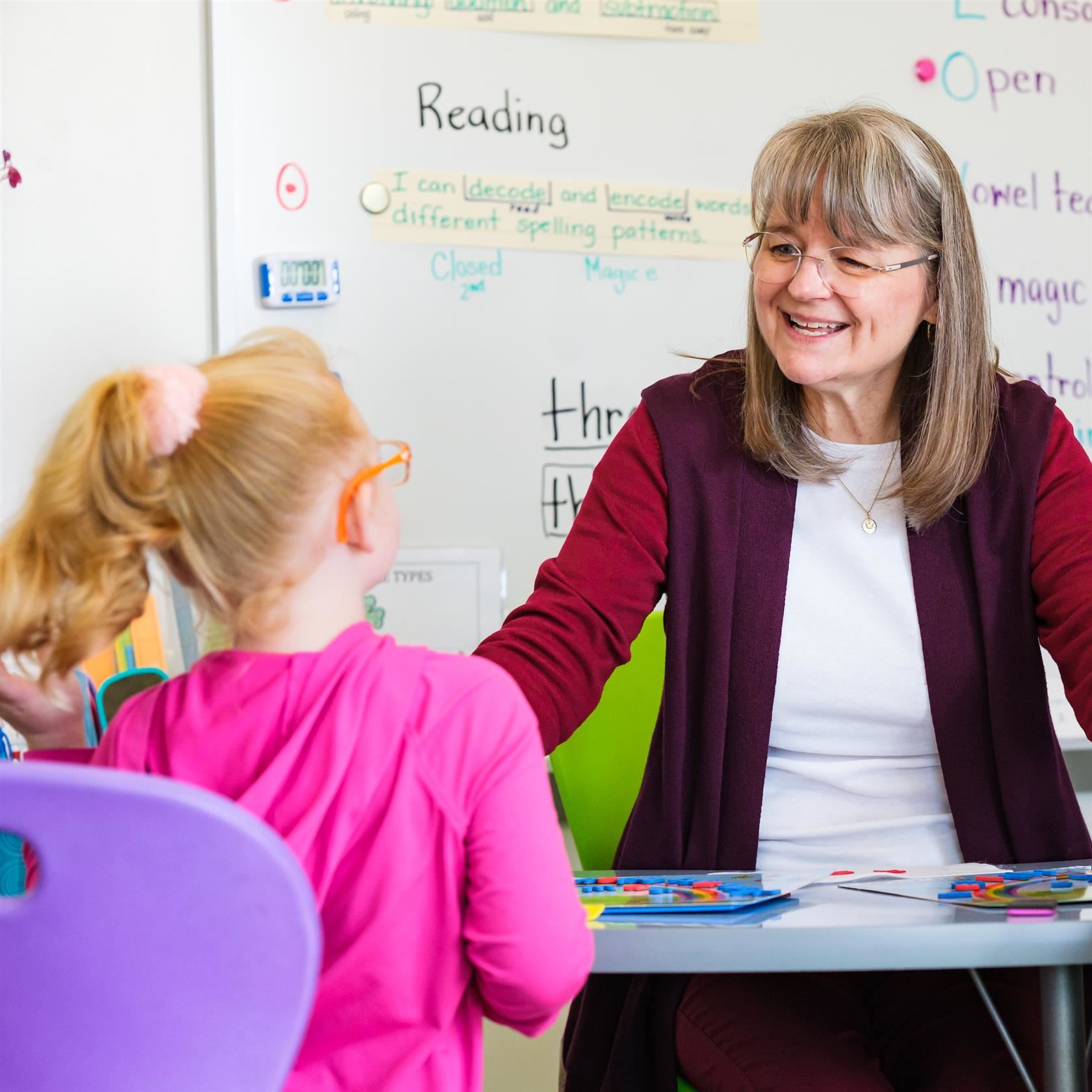 Smiling teacher gives a student individual instruction.