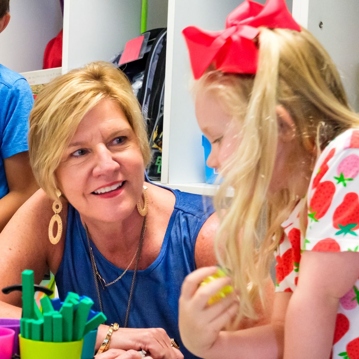 An instructional assistant smiles while helping a student 