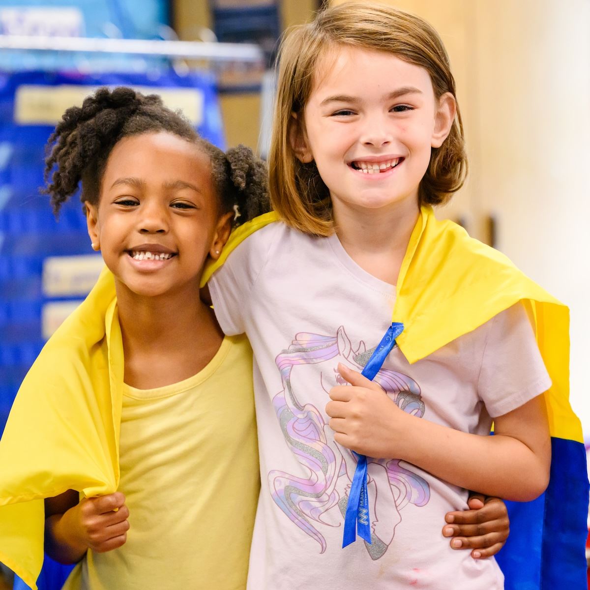  2 students smile while wrapping their arms around each other's shoulders