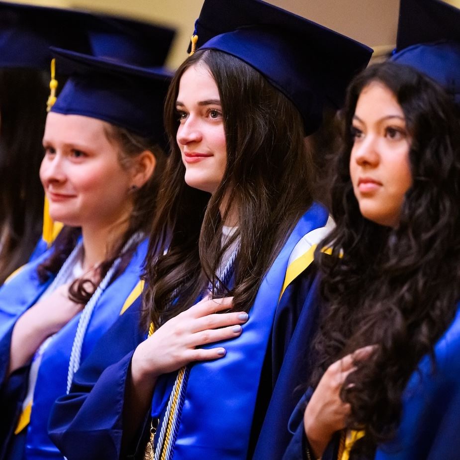  Graduates stand in their caps and gowns