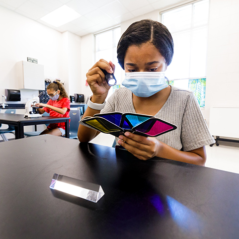  student with flashlight and prism cards