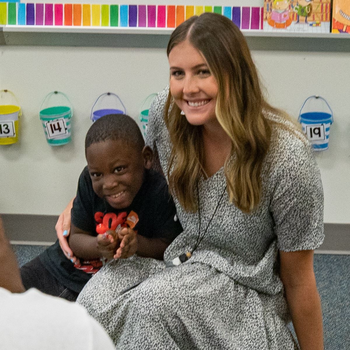  A student grins while kneeling for a photo with his teacher