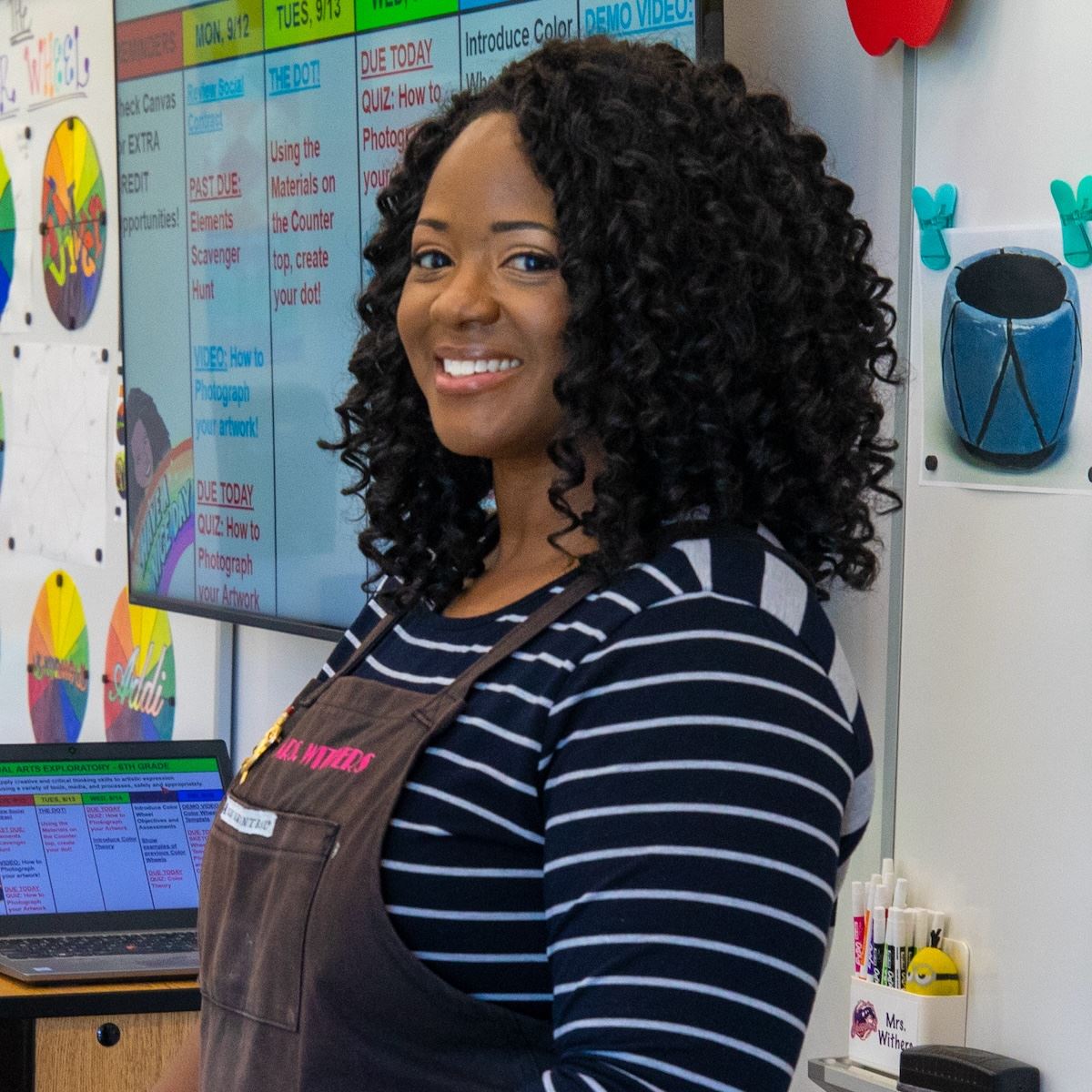  An art teacher smiles while giving instruction to her students