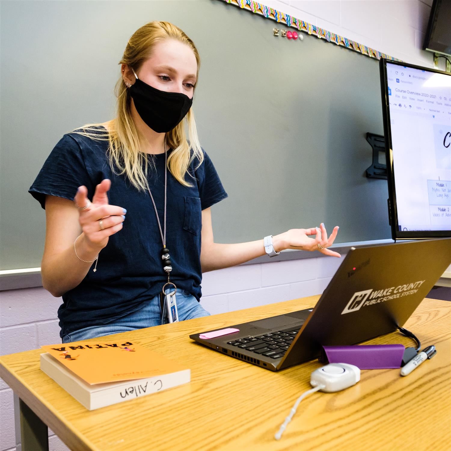  photo of teacher standing in front of a laptop