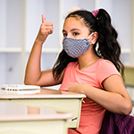  student wearing a mask and raising her hand