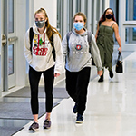  2 girls wearing masks and walking down a hallway