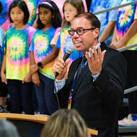 Photo of Principal Tanner Gamble and the student chorus.