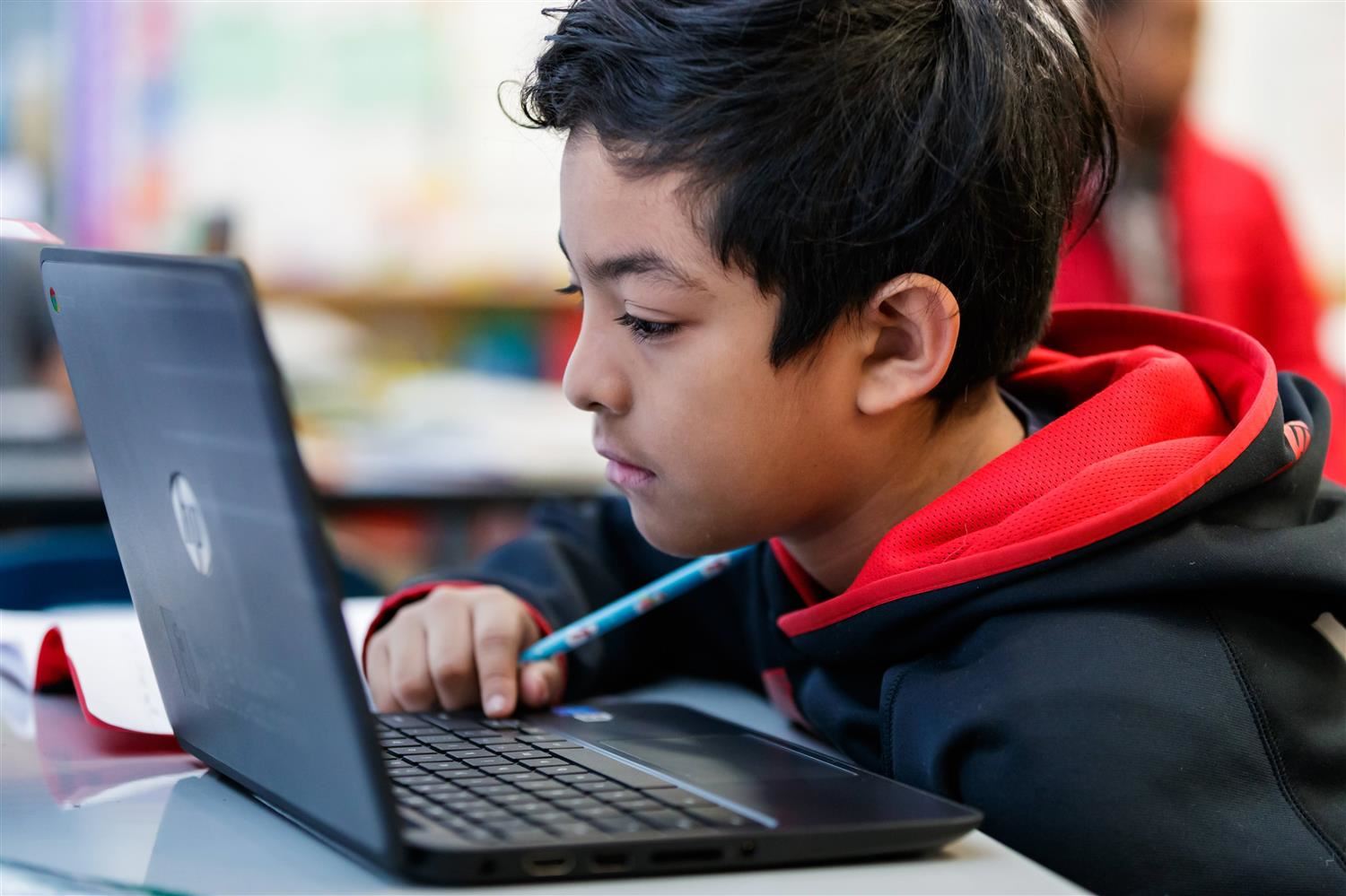 Photo of a student working on a laptop. Photo of a student working on a laptop.