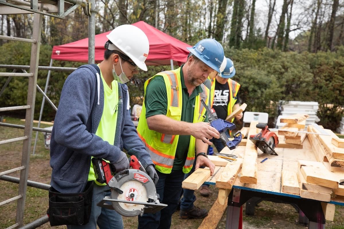 A CTE student works alongside a construction professional