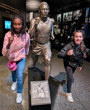 girls running in place with a statute at african american history museum