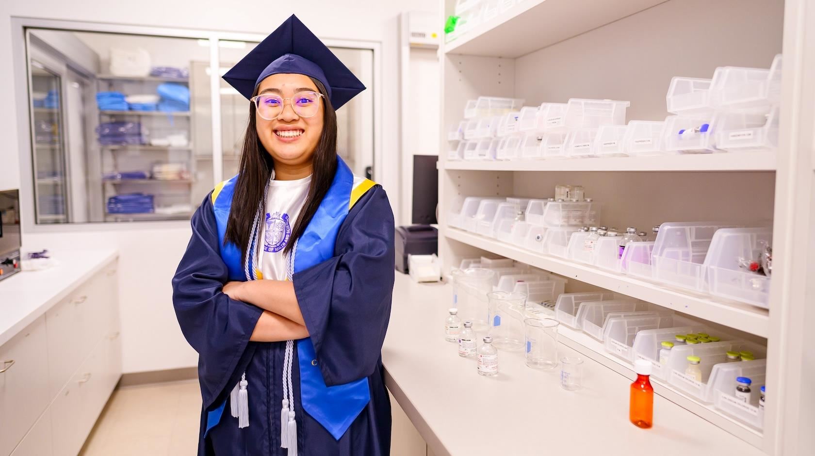 Senior Phuong Nguyen poses in her gown in a medical lab.