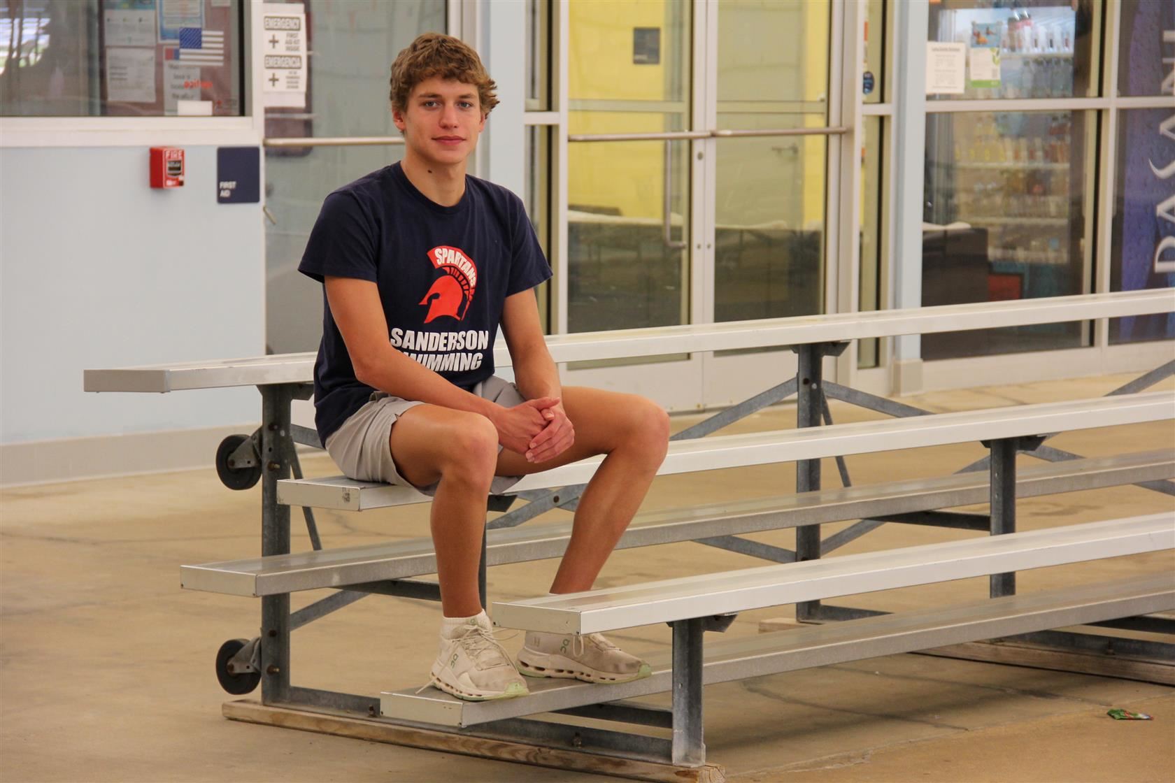 Aaron Davidson sitting on the bleachers at the pool