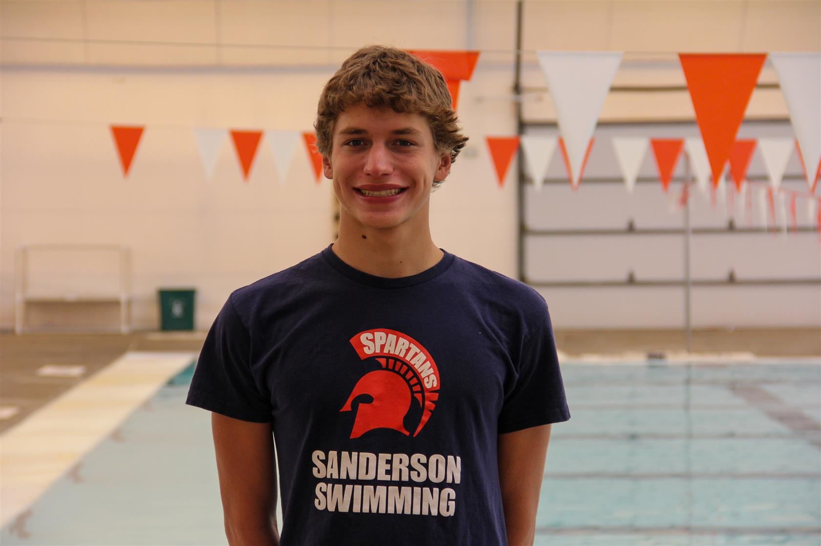Aaron Davidson standing in front of a pool with flags in the background