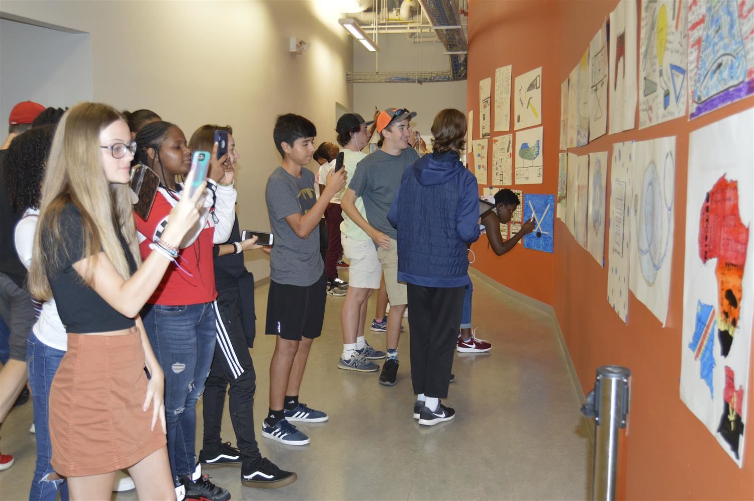 Students using cell phones to read qr codes and gather information on posters.