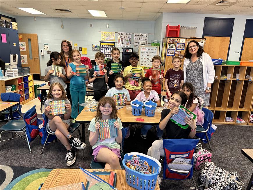 students showing pot holders they made in weaving club